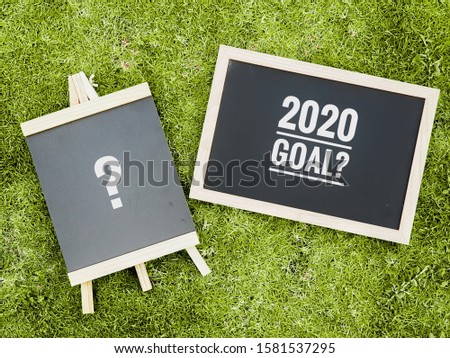Business concept of "2020 Goal?" text written on the chalkboard with the field background.