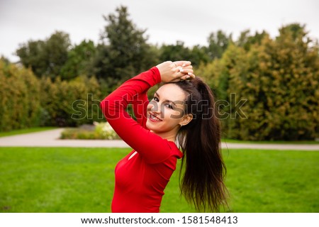 Beautiful girl athlete in red bodysuit training in the park