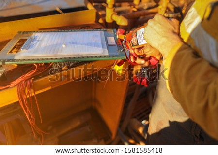 Construction miner placing personal red danger lock which is attached together with danger tag into isolation safety control lock box at the opening field prior to starting work mine site, Sydney    Royalty-Free Stock Photo #1581585418