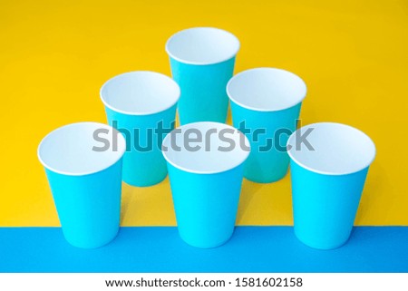 Blue paper disposable cups yellow and blue background. Cooking utensil. Cutlery sign. Top view. Minimalist Style. Copy, empty space for text