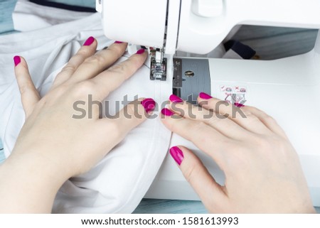 the process of tailoring, woman's hands with a cloth on the sewing machine