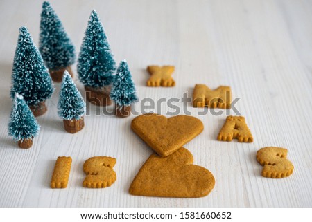 Top view of cookies shaped like letters, hearts and Christmas trees on white background, horizontal