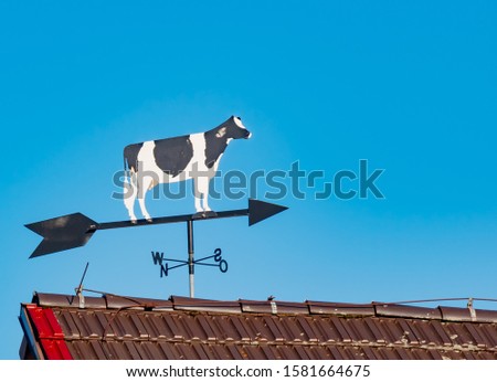 Wind direction, weather, Germany - A weather vane with the picture of a cow, on a day with blue sky without clouds.