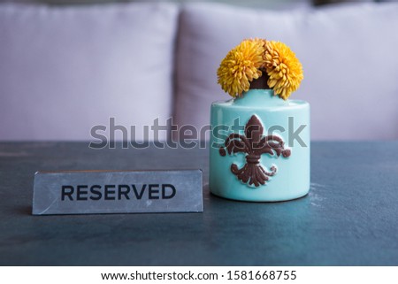 a vase of flowers stands on a dark wooden table on which stands an iron plate reserve