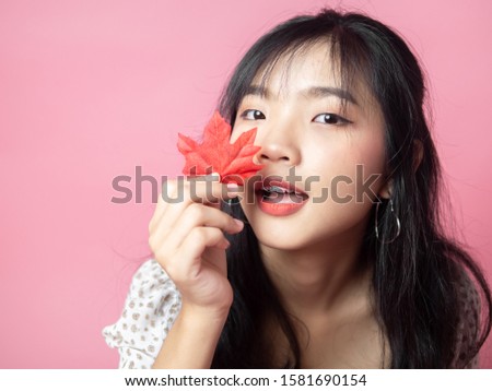 Asian teenager girl with red maple on pink background.