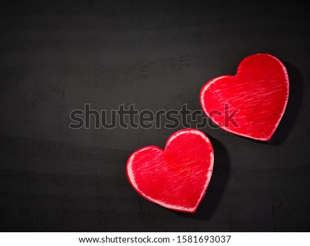 Two hearts on black wooden background