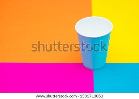 Blue paper disposable cup on beautiful multicolored background. Top view. Minimalist Style. Copy, empty space for text