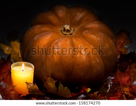 The candle burns before pumpkin with a maple leaf 