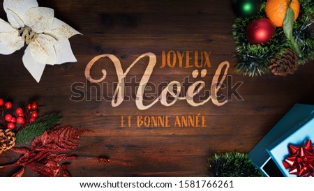 “Joyeux Noel et Bonne Anne” t.i. Merry Christmas and Happy New Year in French language on a wooden background with decoration horizontal view for social media and website home and diary pages