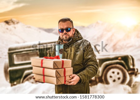 Man in green clothes and landscape of mountains.Green car in snow.Sunny december day and free space for your decoration. 