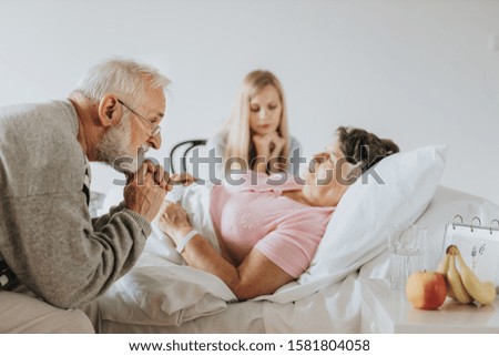 Worried older man sitting by his sick wife's hospital bed