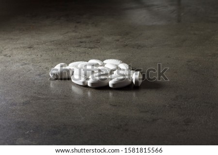 Closeup white oblong pills with signs on gray table background.
