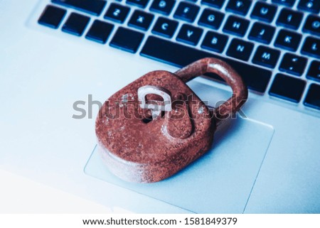 A laptop computer with old rusty lock as symbol of the security risks of outdated software. Selective focus on key