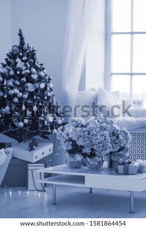 gifts and vase with lush flowers with illuminated garlands and bokeh in background close-up shallow depth of field. Classic Blue color of the year 2020 