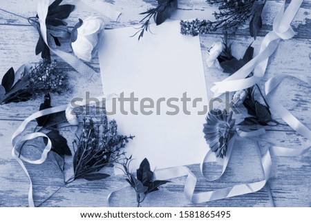 Flat lay with white sheet and flowers and satin ribbons on wooden background top view Classic Blue color of the year 2020 toned picture