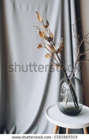 dried flowers in vase on light blue grey fabric background