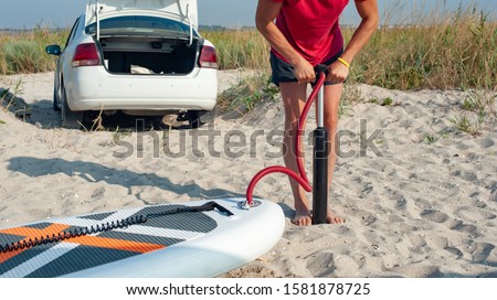 A man took out luggage from his car and inflates a rubber board on the SUP beach on vacation