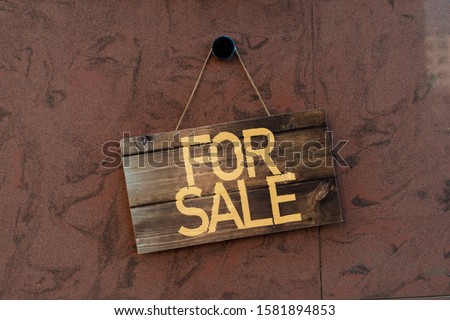 simple sign board frame hanging on the wall of the resident building exterior with word for sale