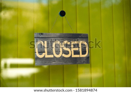the simple sign board frame hanging on the wall of the building exterior with the word "closed", working hours