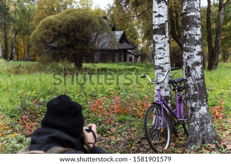a photographer taking a picture of a countryside landscape with a house and a Bicycle