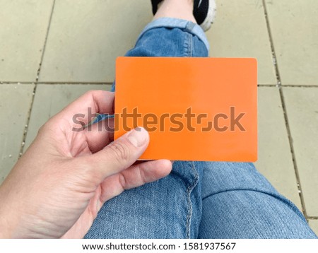 A woman holding an orange card with empty space, copy space for text.