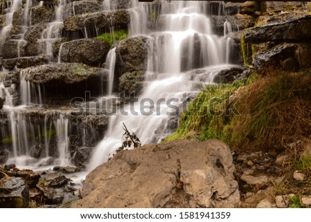 Long exposure photography of multiple springs in a rocky wooded area.