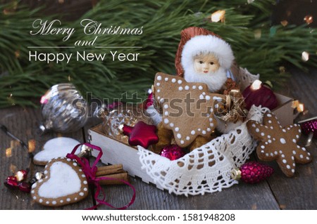 in a wooden box - a doll in an elf costume holds Christmas tree-shaped cookies in its hands, next to it are Christmas decorations and gingerbread cookies. New Year and Christmas card