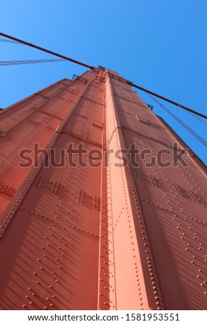 Riveted metal tower from Golden Gate Bridge on blue sky background.