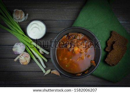red borsch, a traditional national dish of Ukrainian cuisine. uses products such as tomato, potato, beetroot, meat, onions, carrots, beans, cabbage. n the stock photo, the borsch is served in a black 