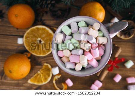 glass with marshmallows on top. wooden background with oranges and cinnamon. christmas picture