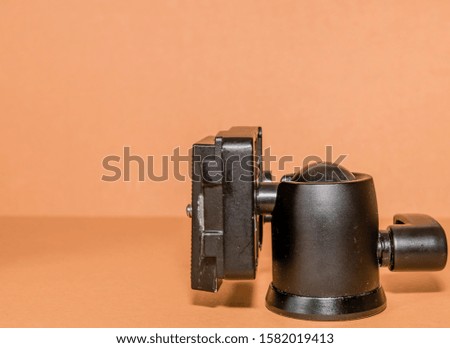 Closeup side view of quick release tripod head on brown background.