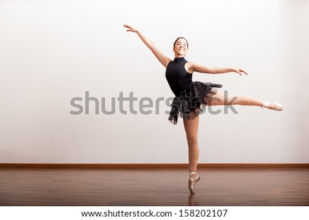 Pretty Hispanic ballerina wearing a tutu and smiling in a dance studio