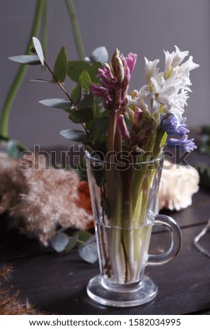 Close-up of hyacinths and eucalyptus branch in a glass cup on a florist's desktop, festive decor, selective focus
