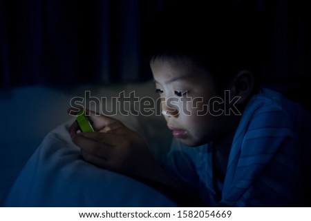 asian chinese boy playing smartphone on bed with noise and soft focus, kid use phone and play game, addicted game and cartoon, 
