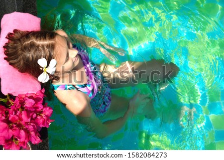 Girl enjoys in the pool. A relaxing holiday at sea. Beauty spa concept for body. Child girl swims in the water. Tropical vacation. Holidays on the ocean. 