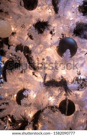 Black Feathers and Ornaments on a White Christmas Tree Close Up