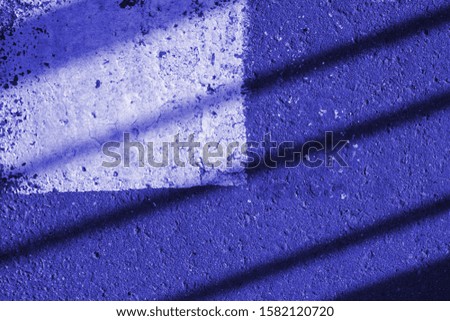 Asphalt surface with white paint and shadows close-up. Abstract background blue color toned