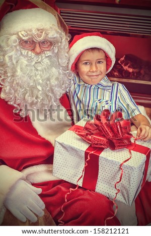 Santa Claus giving a present to a little cute boy at home.