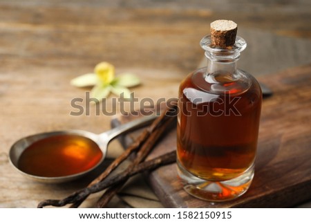 Aromatic homemade vanilla extract on wooden table, closeup. Space for text Royalty-Free Stock Photo #1582150915
