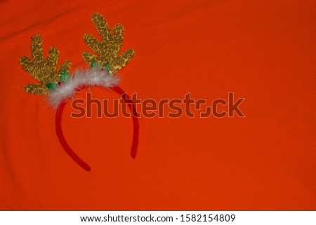 Christmas antlers of a deer with bells on orange background. Pair of toy reindeer horns. Merry Christmas and Happy New Year symbol.