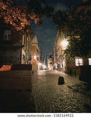 A vertical shot of buildings on a stone road in a city during nighttime
