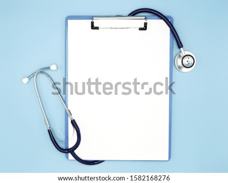 Flat lay of stethoscope and writing pad paper clip board on light blue background with copy space, healthcare and medical concept, top view photo. Royalty-Free Stock Photo #1582168276