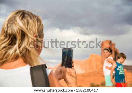 Woman taking pictures of her two children while visiting national park in summer season.