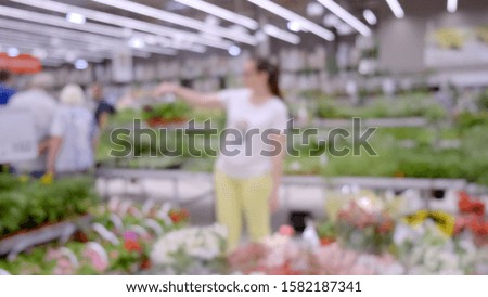 The girl in the supermarket chooses a basket of vegetables. Soft focus