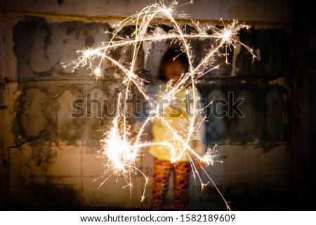 Asian children are playing with fireworks in different ways. Make it look strange and beautiful.    