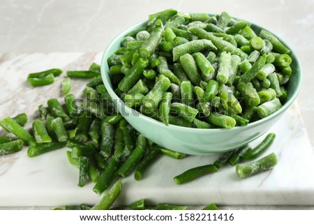 Frozen green beans on light grey marble table, closeup. Vegetable preservation