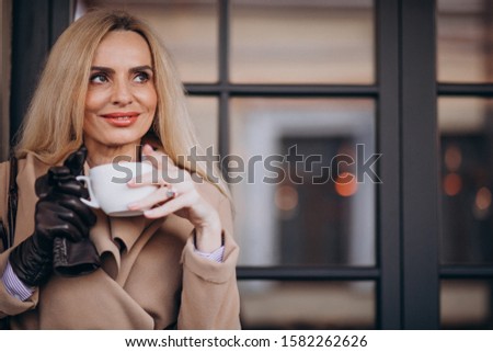 Elderly woman drinking coffee outside the cafe