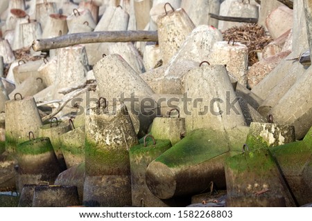 The seawall around the sea port facilities is made of concrete tetrapods (traveling-wave protection), rubble-mound breakwater. There's lot of debris thrown out by storm Royalty-Free Stock Photo #1582268803