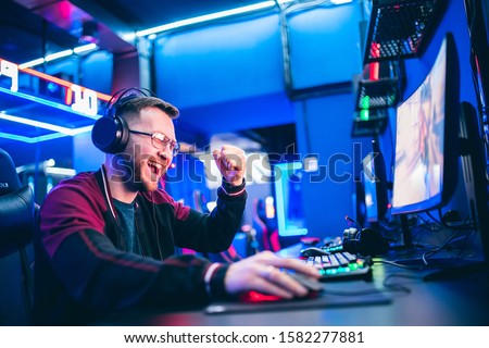 Professional gamer playing tournaments online video games computer with headphones, red and blue.