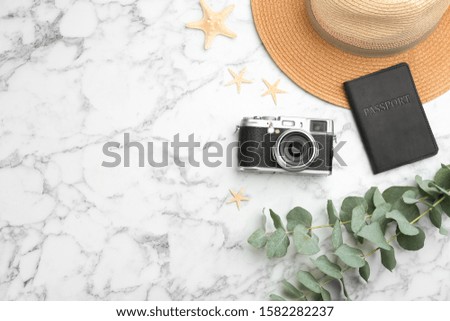 Flat lay composition with professional photographer camera, passport and space for text on white marble table